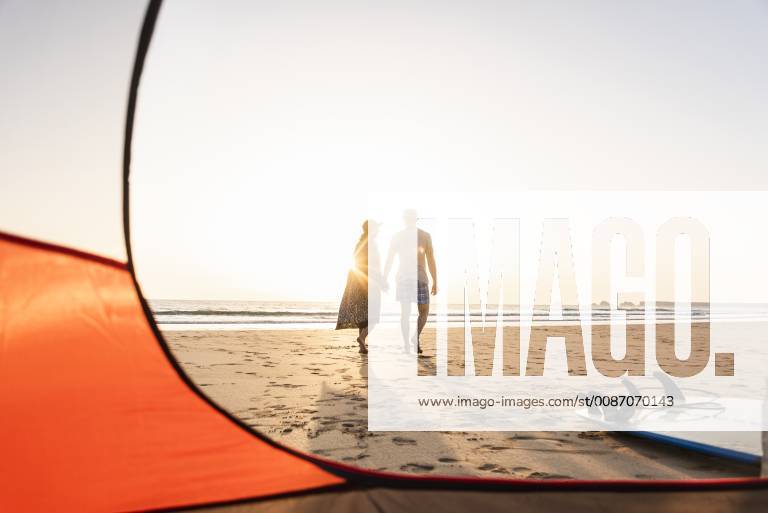 Romantic couple camping on the beach, doing a beach stroll at sunset model released Symbolfoto UUF15148