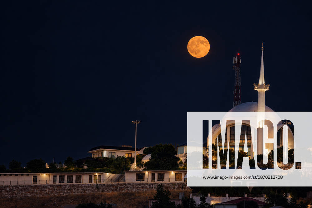 A glowing full moon illuminates the night sky behind a modern illuminated mosque in Erbil Iraq on October 26 2026 Erbil Iraq - ZUMAr205 20261026_zip_r205_001