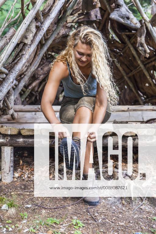 Young woman sitting on bench lacing her hiking boots model released Symbolfoto property released TCF05834