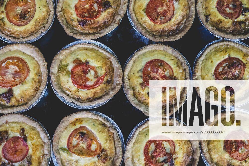 High angle close up of freshly baked quiches with a cheese and tomato topping. High angle close up of freshly baked quiches with a cheese and tomato topping. 44341