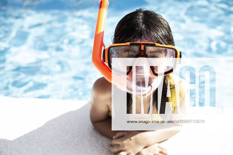Portrait of little girl wearing snorkel and oversized diving goggles leaning on poolside model released Symbolfoto ERRF00162