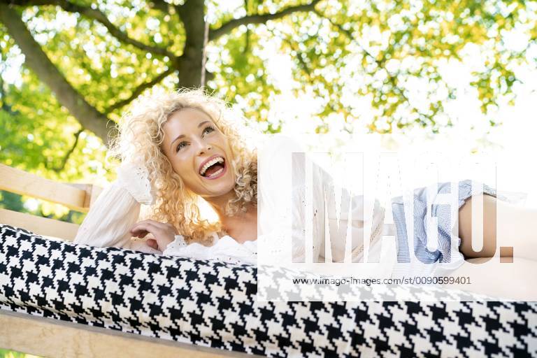 Happy young woman lying on a bed in garden model released Symbolfoto property released PESF01344
