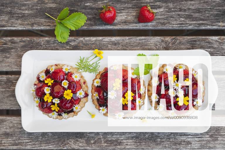 Homemade strawberry heart tartlets with daisy flowers and golden marigold, edible flowers, dark wood GWF06024