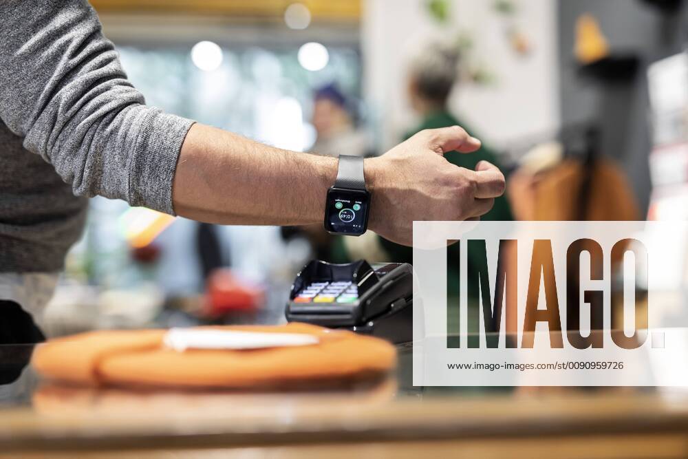 Customer paying contactless with his smartwatch model released Symbolfoto property released PESF01529