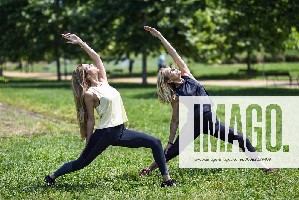 Mature woman doing yoga with her daughter in a park model released Symbolfoto JSMF01143