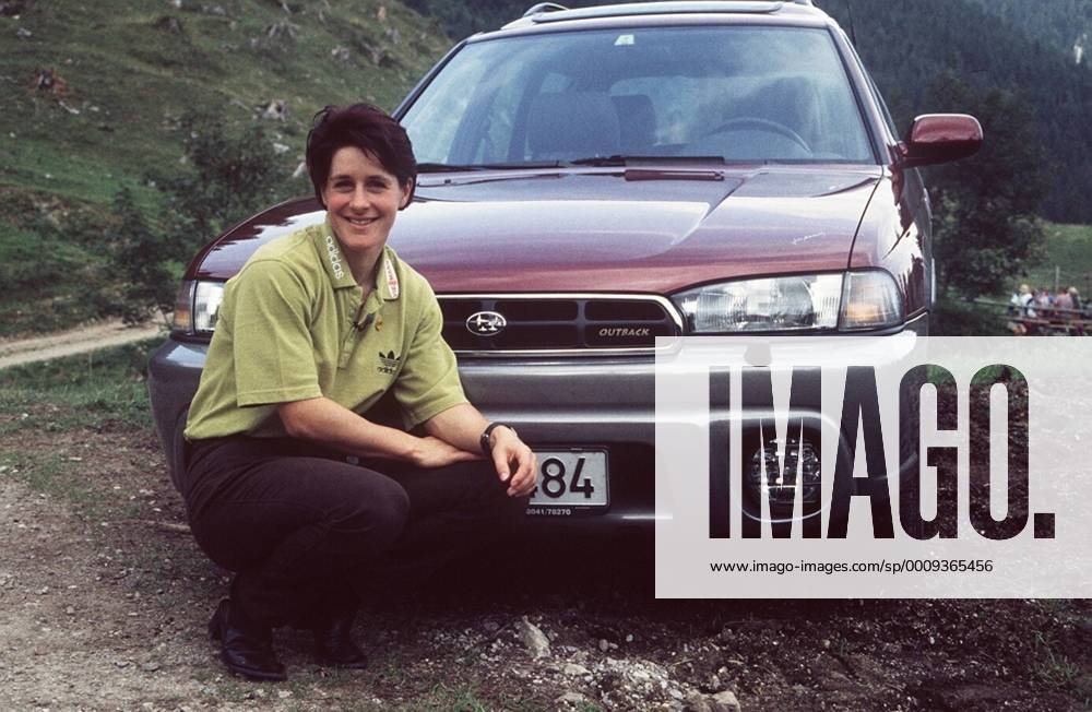 Uschi Disl mit Subaru Legacy in auto motor und tv (VOX) 09 98 böw Frau Weltmeisterschaft Biathlon dunkelhaarig kurzhaarig leger Shirt Hose Landschaft Gebirge Auto Wagen Kennzeichen kniend lächelnd ganz quer