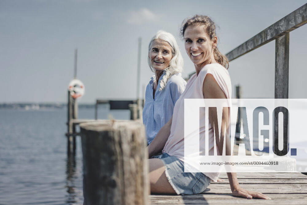 Mother and daughter sitting on jetty, relaxing at the sea model released Symbolfoto JOSF03708