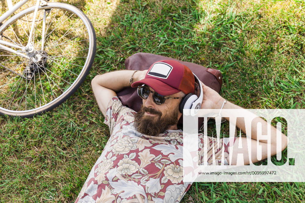 Mature man with red basecap, sunglasses and white headphones model released Symbolfoto TCF06227