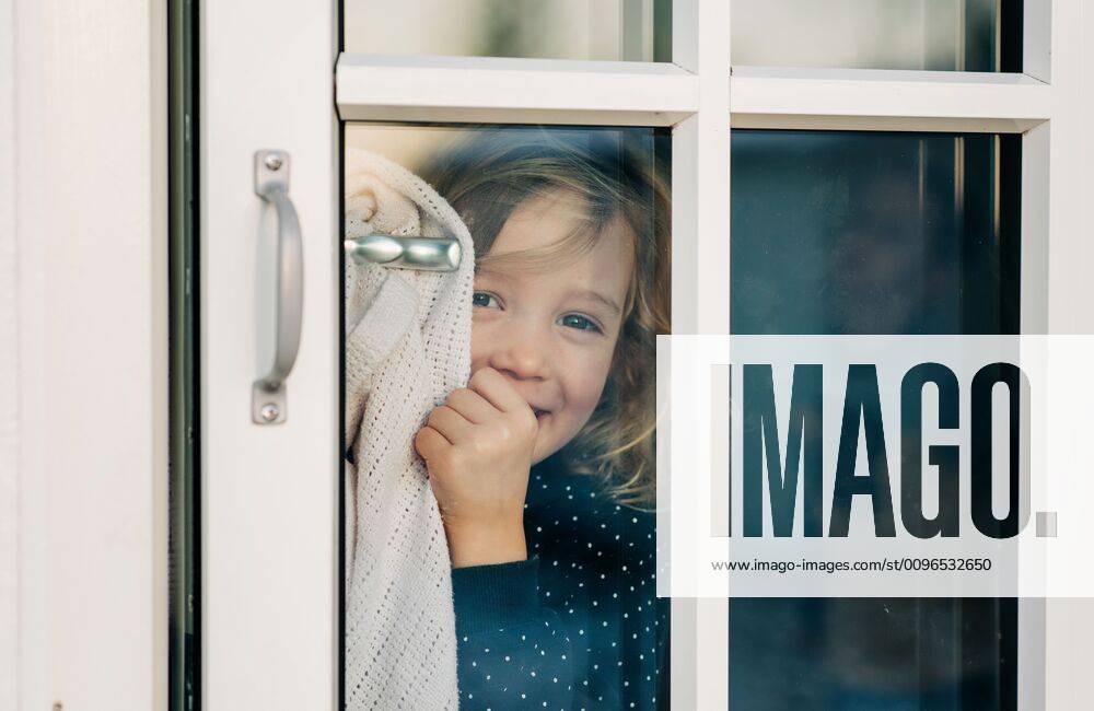 IMAGO Creative, Jahreszeit Sommer, Sommerferien young girl looking through a door window smiling looking happy Stockholm, Stockholm County, Sweden CR_RABE191212-252792-01