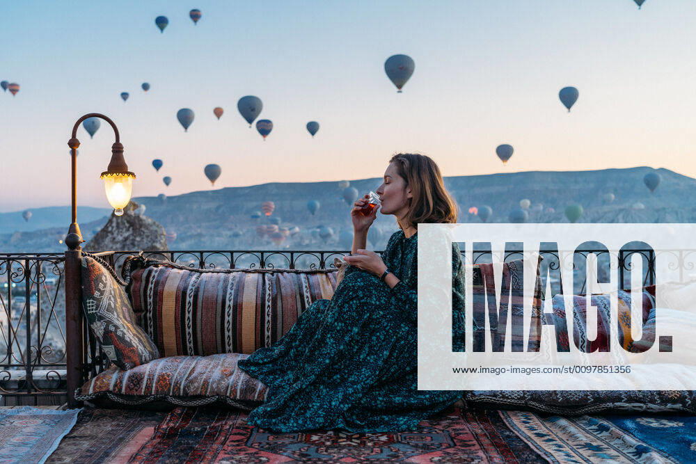 Woman drinking early morning tea with hot air balloons in Cappadocia GoÂ¶reme, NevAÂüehir, Turkey ,model released, Symbolfoto CR_SEAK200116B-287292-01