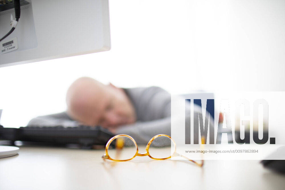 Photo presented on the subject of naps in the office, Bonn, den 11 03 2020 A man has taken off his glasses and is sleeping at his desk Bonn Germany