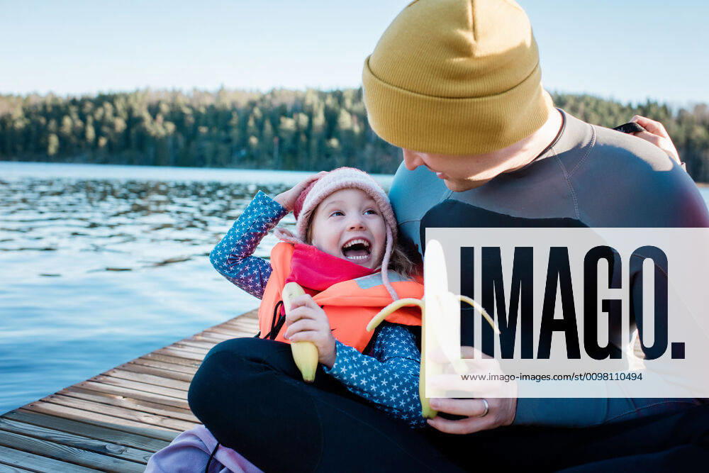 IMAGO Creative, Jahreszeit Sommer, Sommerferien father and daughter eating fruit laughing at the beach on vacation NorrtoÂ¤lje, Stockholm County, Sweden ,model released, Symbolfoto CR_RABE200224-308721-01
