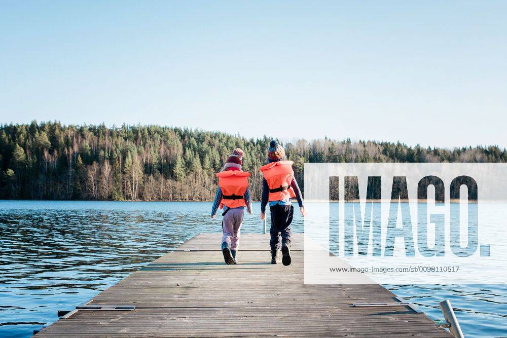 IMAGO Creative, Jahreszeit Sommer, Sommerferien brother and sister walking along a pier in winter with life vests on NorrtoÂ¤lje, Stockholm County, Sweden ,model released, Symbolfoto CR_RABE200224-308739-01