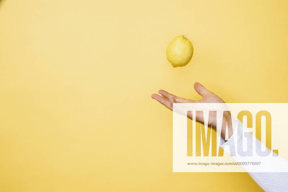 Studio shot of hand of person tossing up lemon model released Symbolfoto DAWF01394