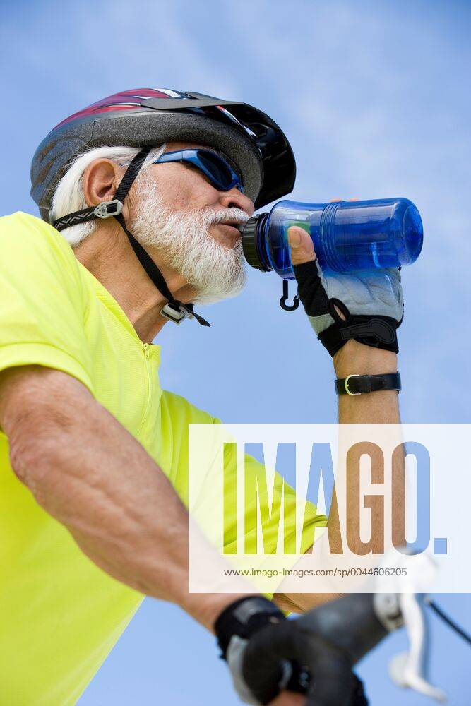 Senior man cycling and drinking water