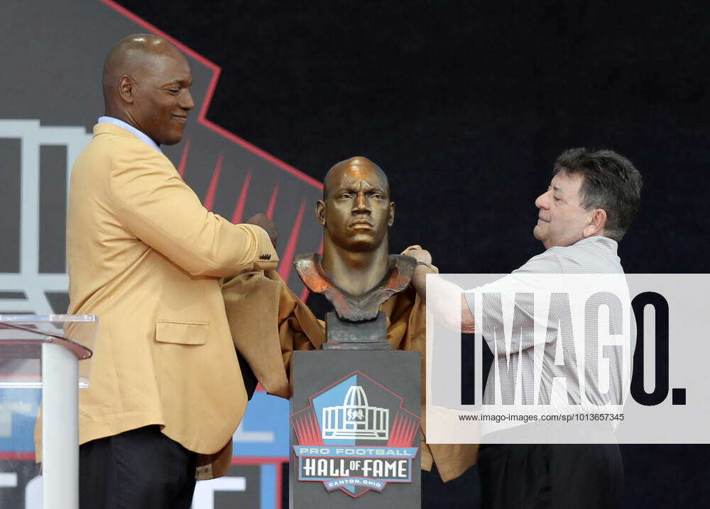 Former NFL player Bryant Young, right, poses with his bust and