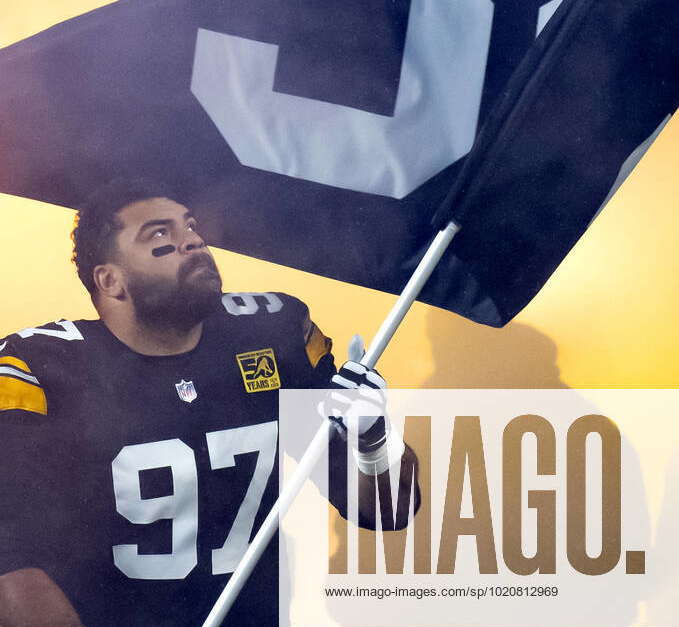 Pittsburgh Steelers defensive tackle Cameron Heyward (97) carries a flag  with Franco Harris number 32 on to the field before the start of the game  against the Las Vegas Raiders at Acrisure