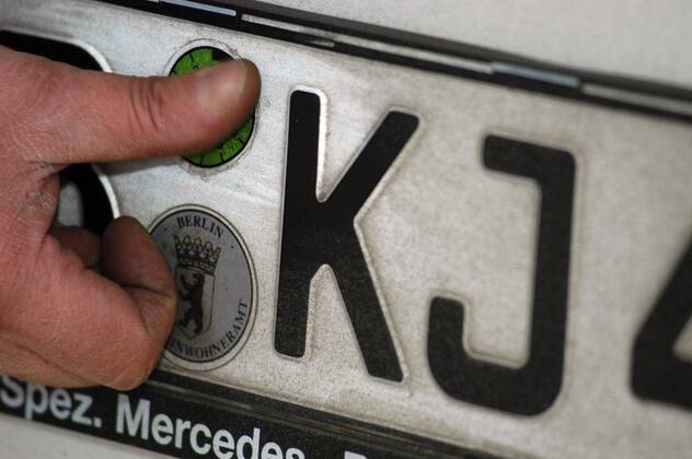 Neue TÜV-Plakette wird auf ein Nummernschild