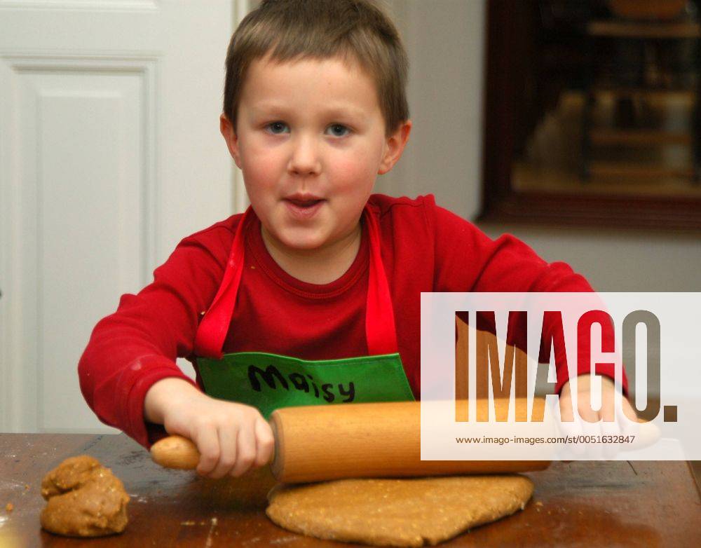 Weihnachtsbäckerei - Kleiner Junge rollt Teig für ein