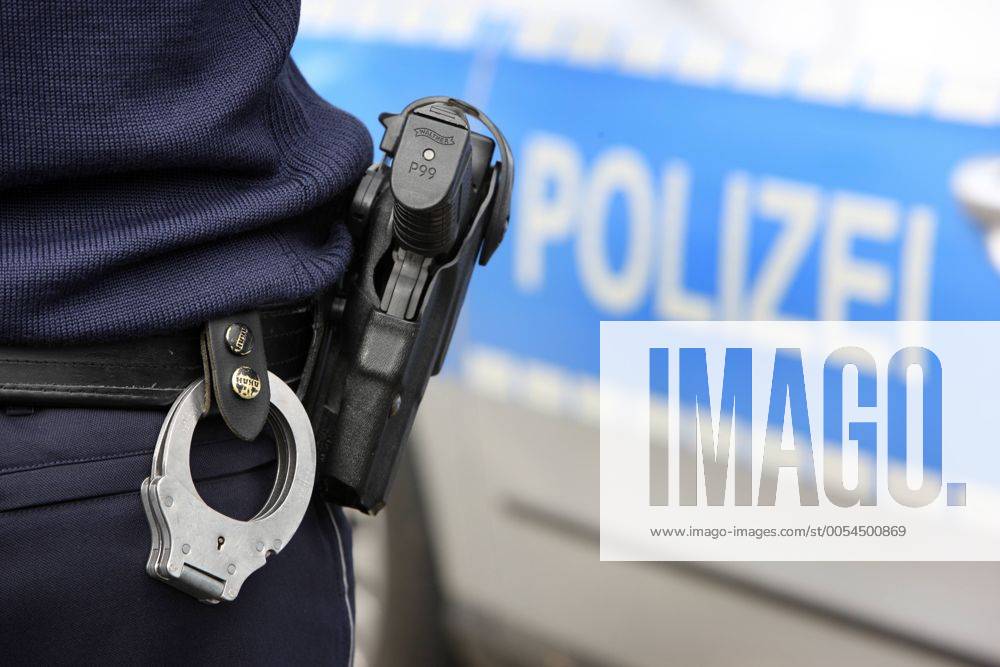 Polizei, Streifenwagen. Polizist mit Handschellen und Dienstwaffe, Walther P99, im Holster