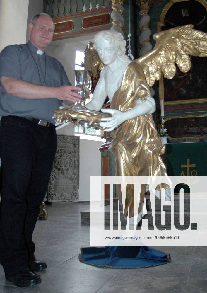 Pfarrer Martin Fromm neben dem Taufengel der evangelischen Kirche St