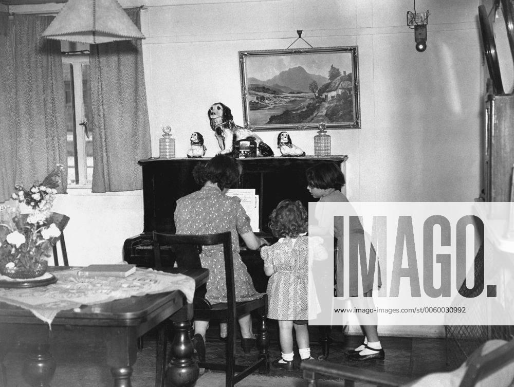 Mrs Kemp plays the piano in the living room for Annette and Gwyneth