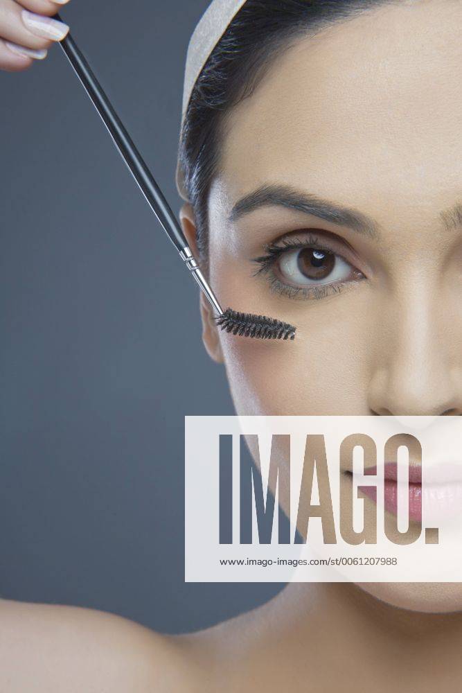 Cropped image of beautiful young woman using eyebrow tinting applicator