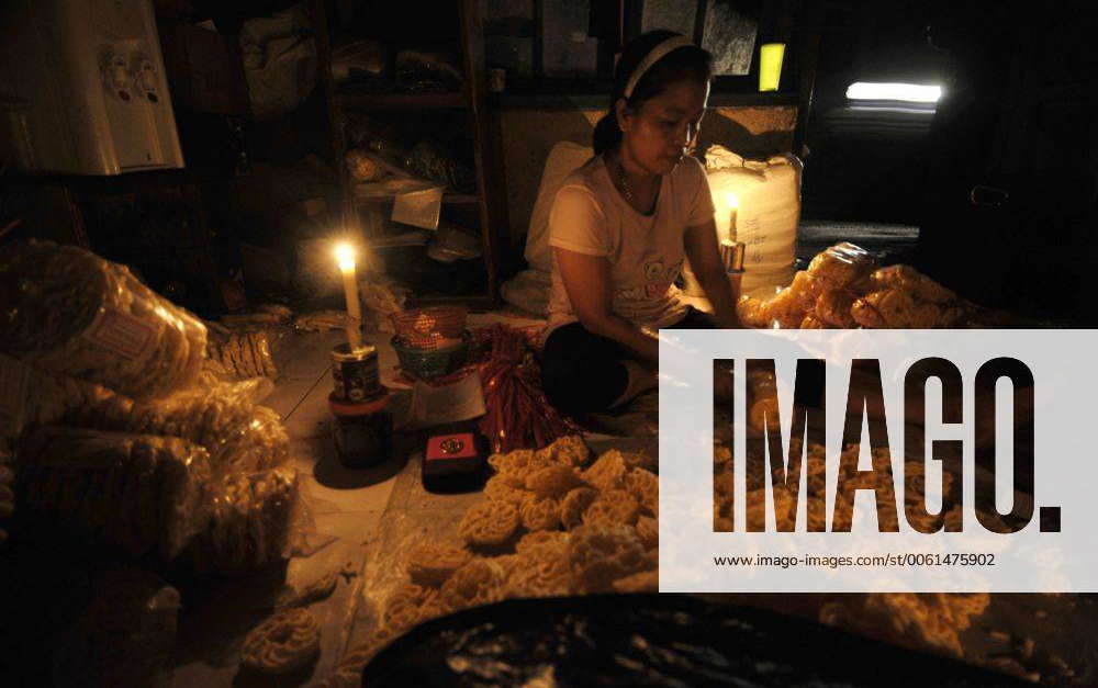 Women packages crackers beside candles because of power outage in southern  Jakarta, Indonesia, May