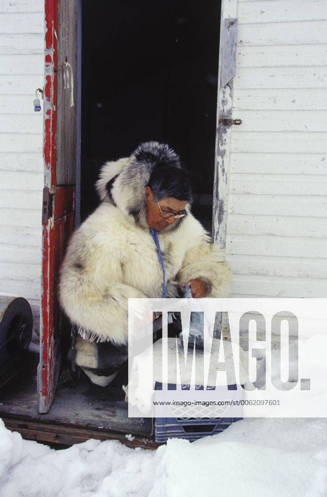 Inuit elder works on soapstone carving in traditional clothing
