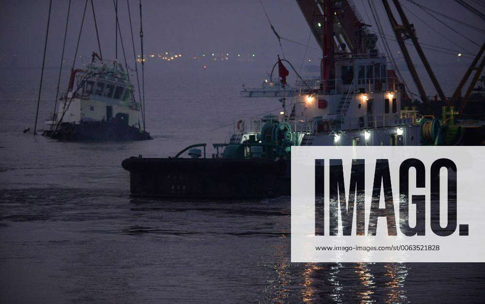 A salvage vessel (R) helps lift the wreckage of capsized tug boat ...