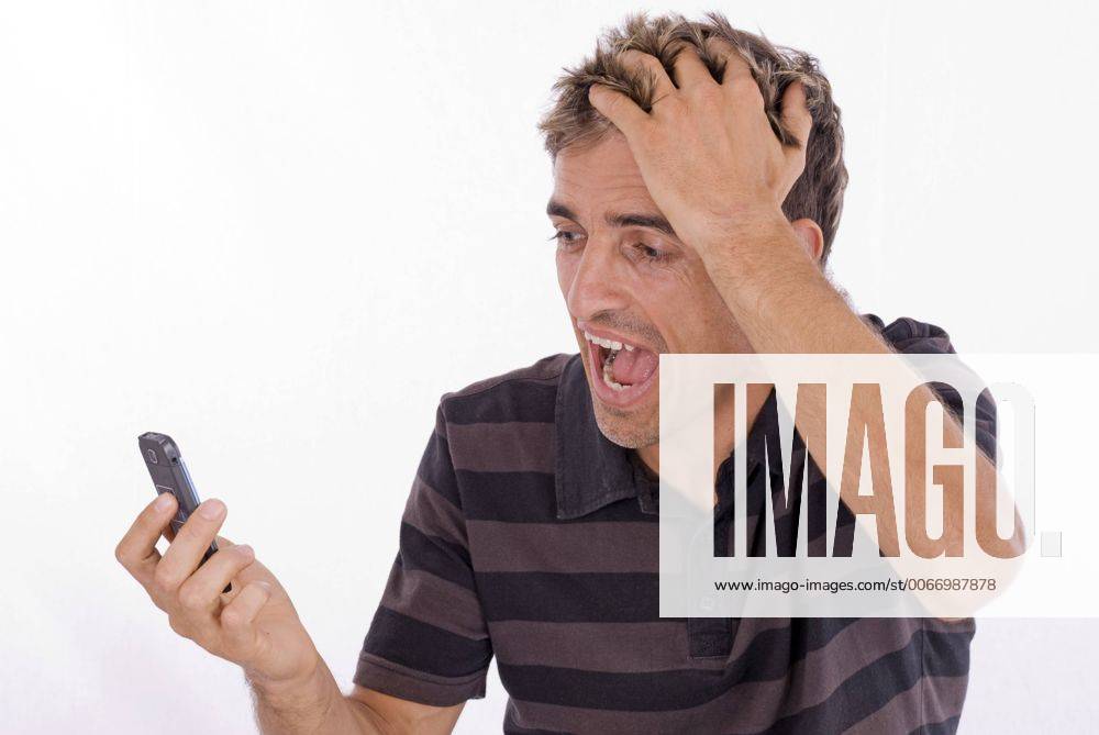 Mann fasst sich an den Kopf und schreit sein Handy an man holding his head screaming at his mobile