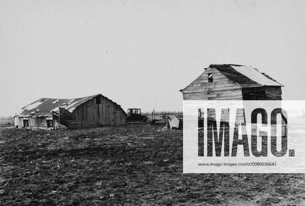 A hay house and corn crib, both in various stages of collapse, situated