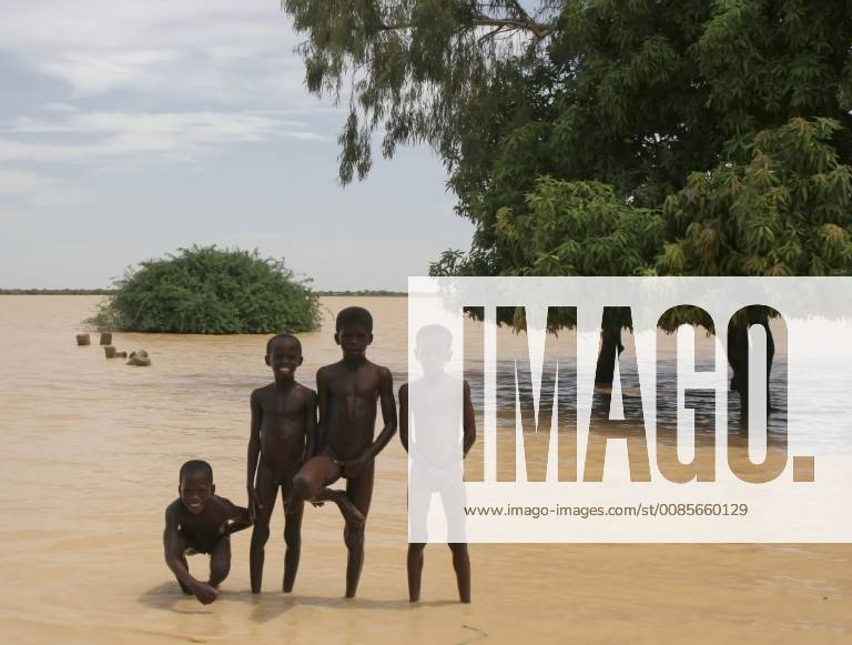 Four naked African Songhai children standing on the edge of a large