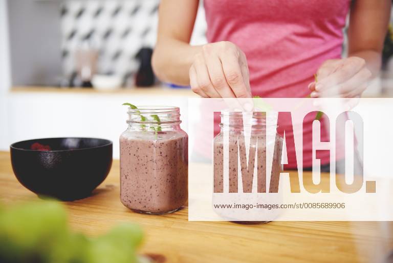 Woman s hand garnishing glass of raspberry smoothie model released
