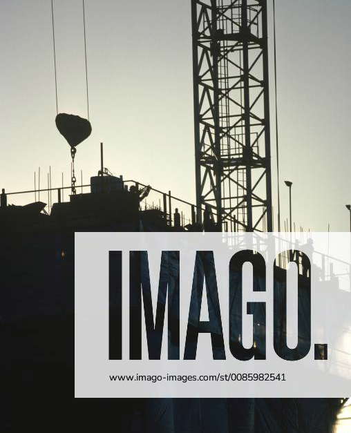 Commercial construction site with silhouette of crane hoist, rebar and ...