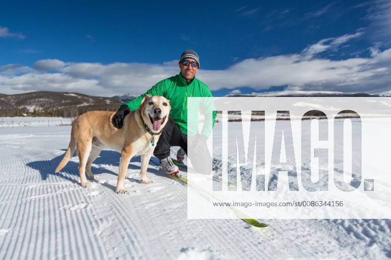 Man petting dog while taking a break from cross country skiing, Winter