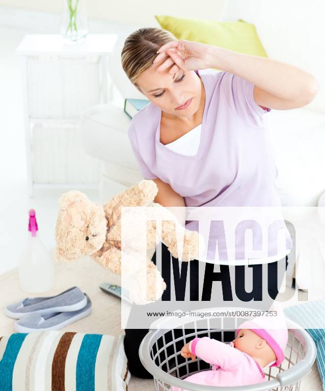 Exhausted Young Woman Putting Toys Into A Basket In The Living Room