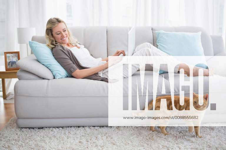 Pretty Woman Lying On Sofa Using Her Laptop At Home In The Living Room