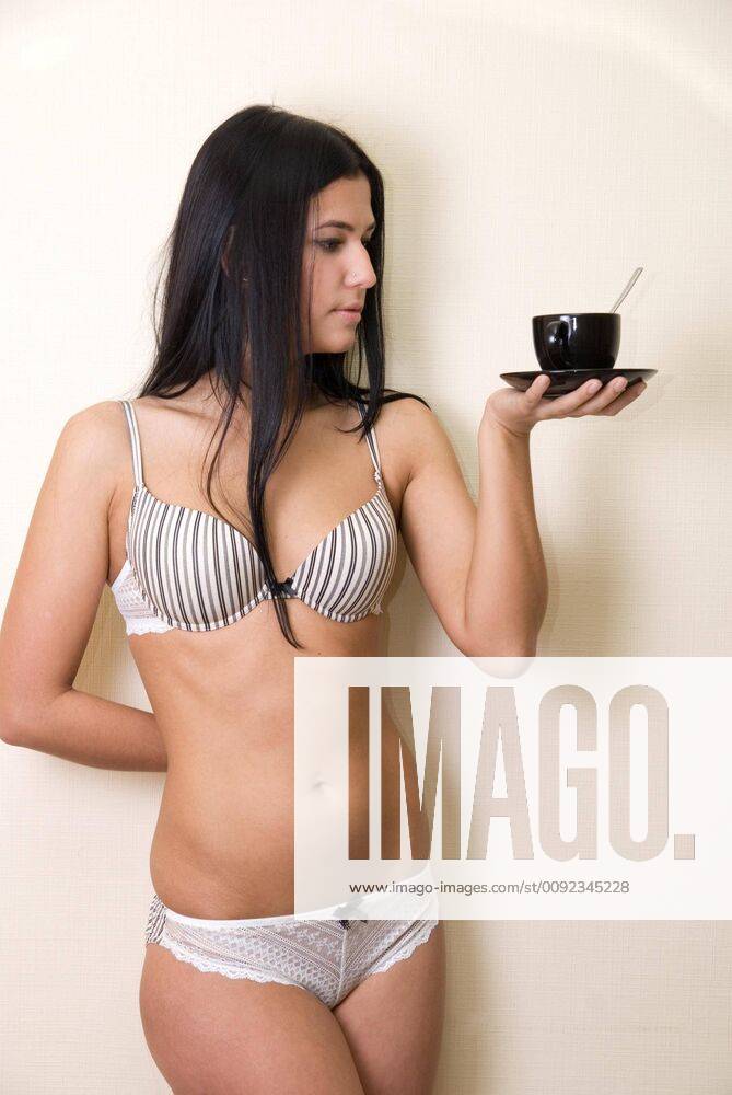 Sexy girl in lingerie at wall background with coffee cup model