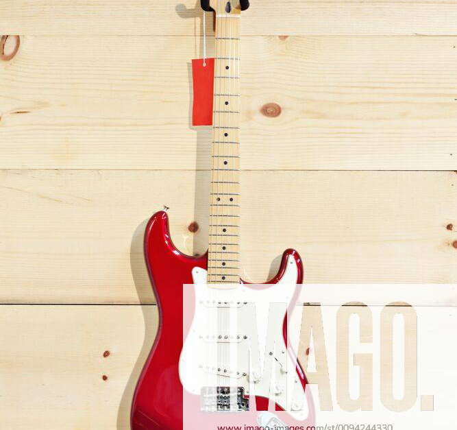 Fender Stratocaster red and white guitar on wood grain wall,property