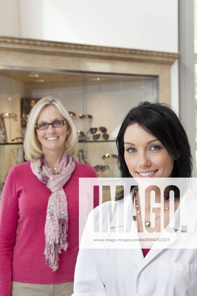 Portrait of happy mid adult optician and customer wearing glasses,model released