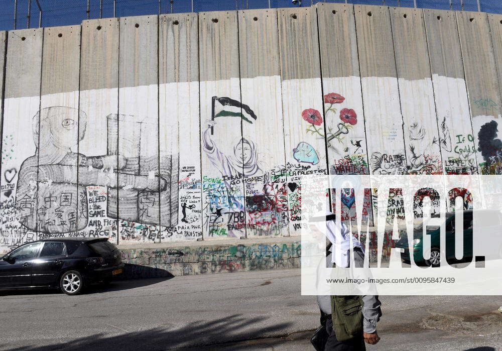 A Palestinian walks past the Israeli separation wall in the biblical ...