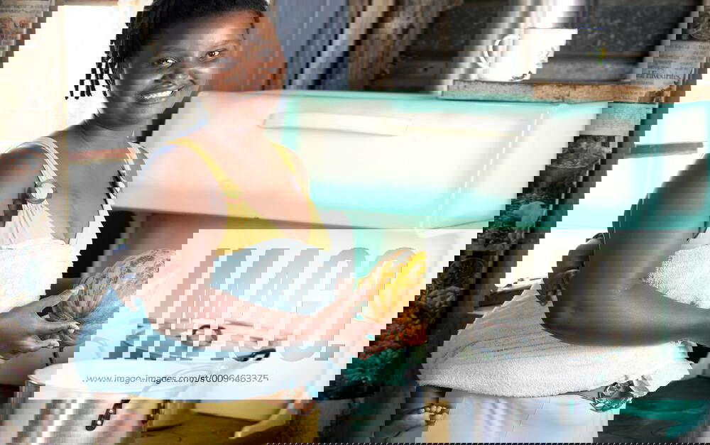 Young black female cooking in her kitchen, smiling at camera