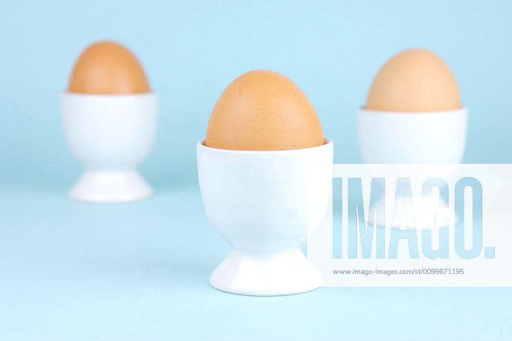 Hard Boiled Eggs Hard boiled eggs and egg cups isolated against a blue ...