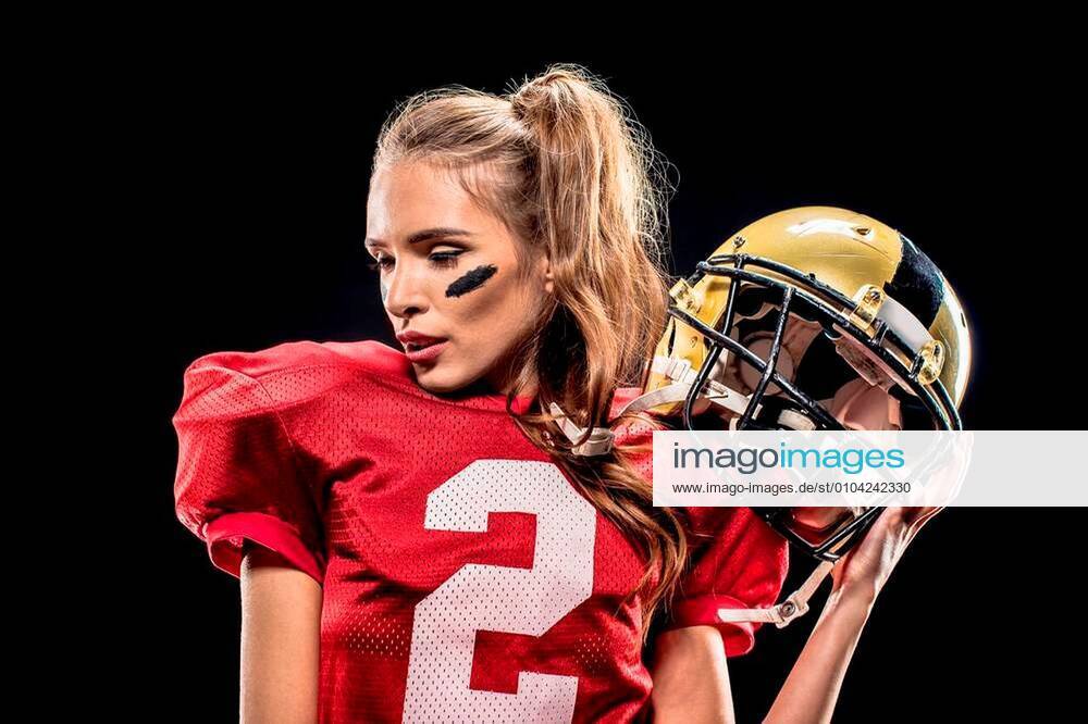 Attractive female american football player in uniform posing with helmet on  black xFotosearchxLBRFx