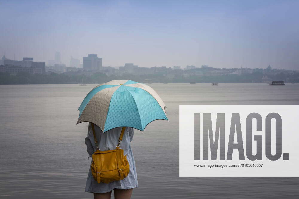 China, Zhejiang, Hangzhou, Women with umbrella looking over the West lake