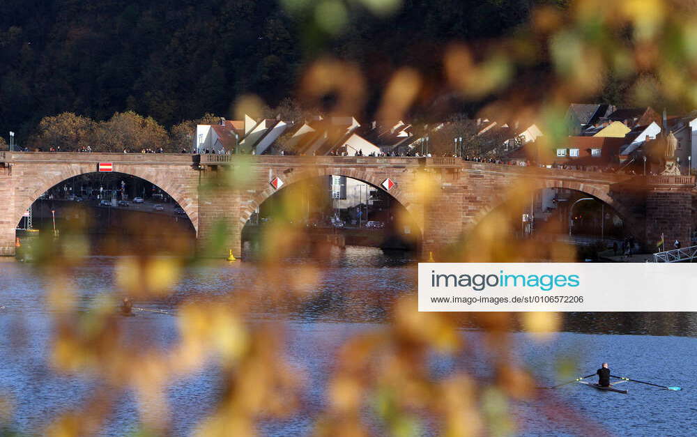 The Old Bridge in Heidelberg shines through colorful autumn leaves on a ...