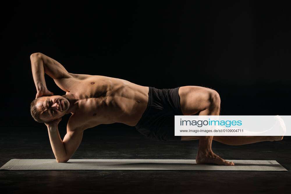 Man standing in yoga position Athletic man practicing yoga in vasisthasana  side plank variation