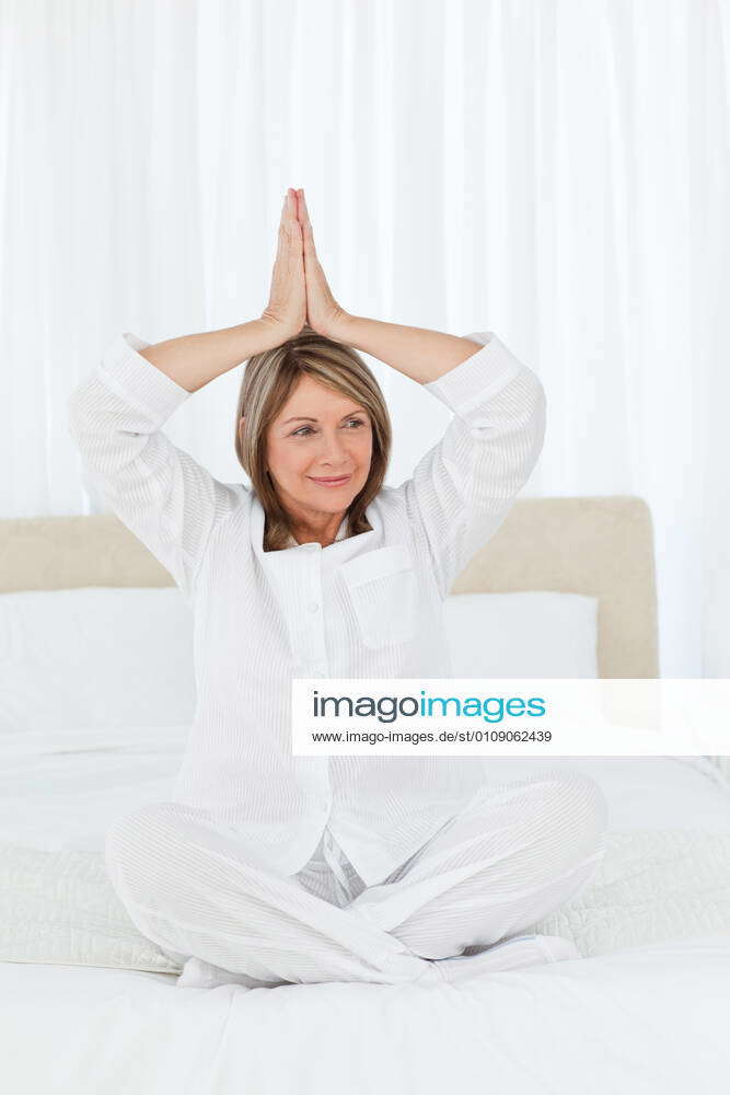 Senior practicing yoga on her bed Senior practicing yoga on her bed at ...