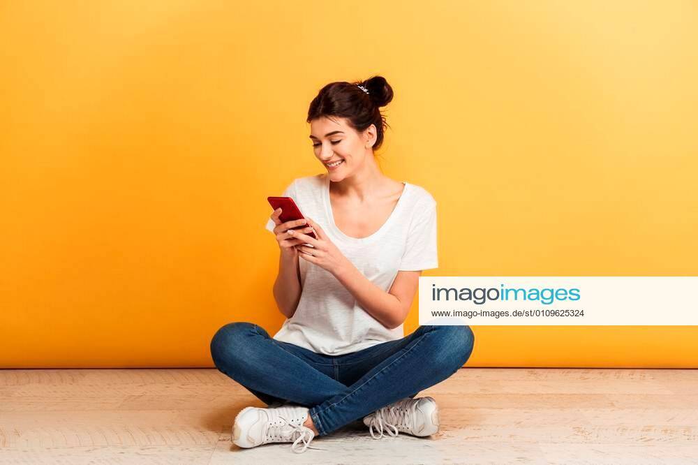 portrait-of-a-smiling-young-woman-using-mobile-phone-while-sitting-with